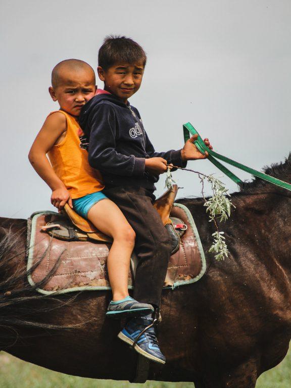 Central Asia Travel Tips: 50 Things to Know and Do Before You Visit kids on a horse in kazakhstan