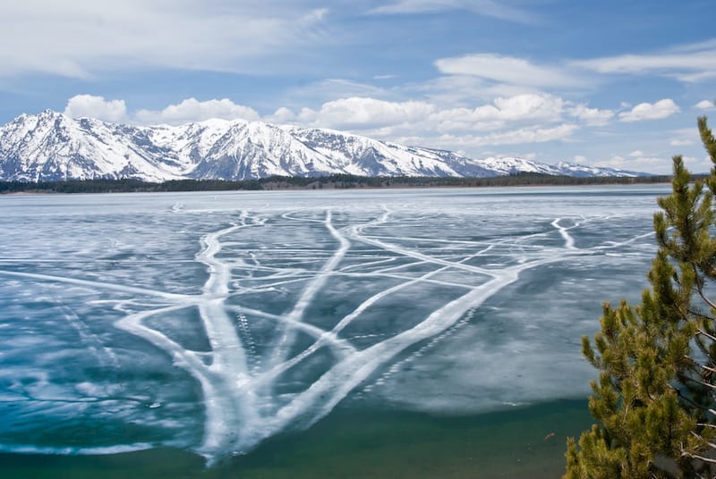 Cracks in the ice of Jackson Lake with Teton range in background