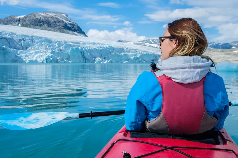 Woman kayaking on Styggvatnet glacier lake near Jostedalsbreen glacier. Norway.