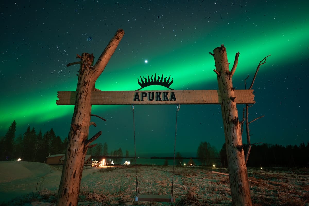 the northern lights over a sign for a resort in lapland