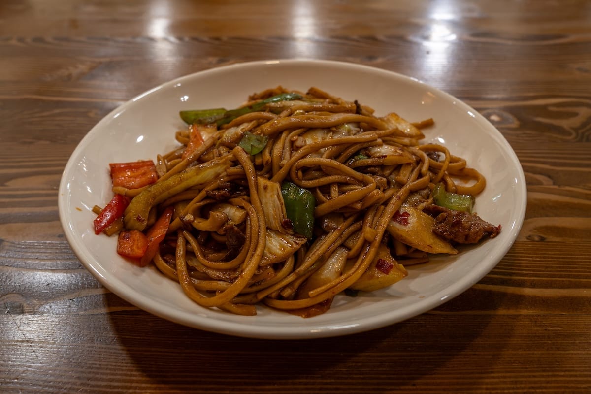 a bowl of fried noodles, bell peppers, and meat at a restaurant
best restaurants in almaty, kazakhstan
