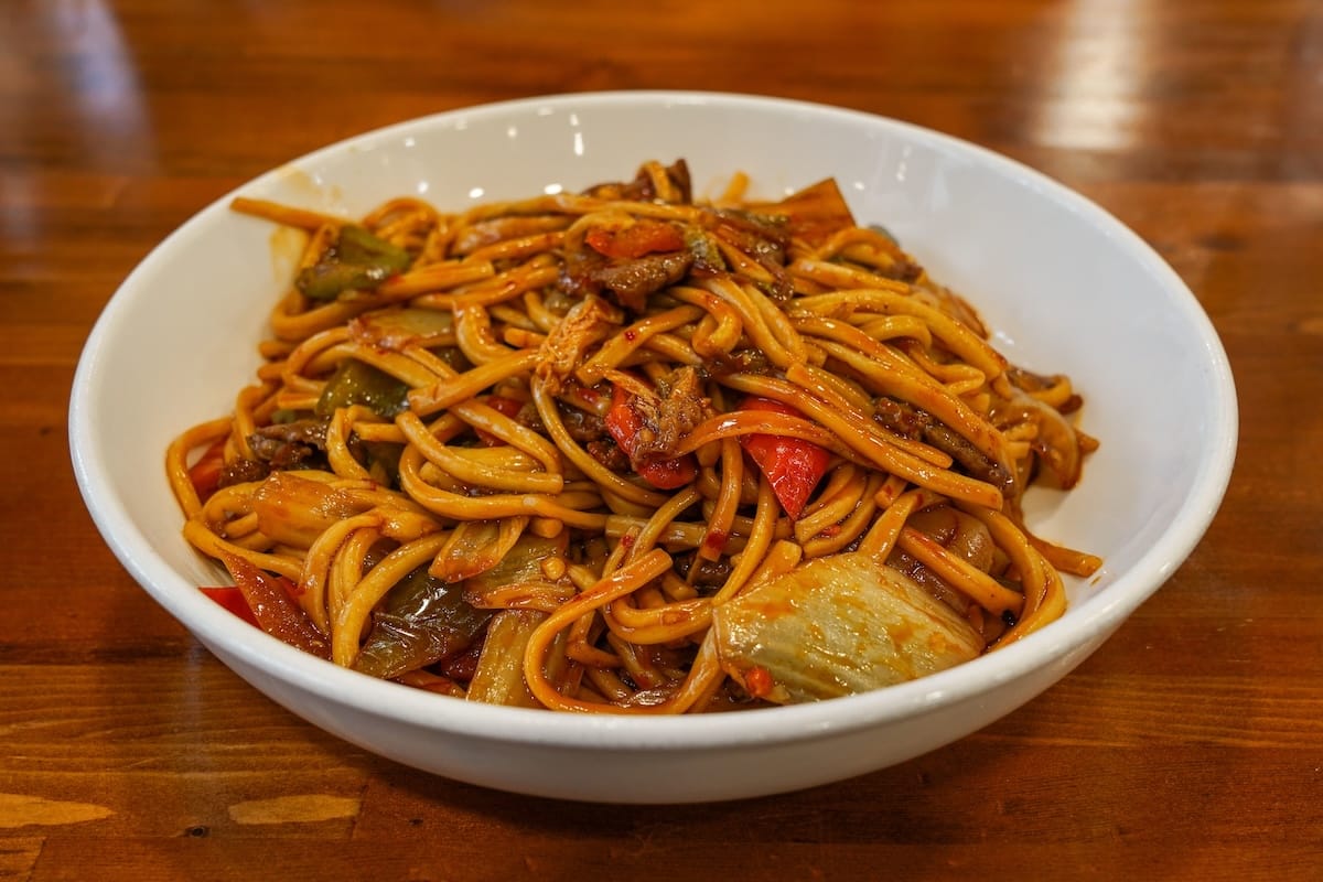a bowl of laghman fried noodles on a table