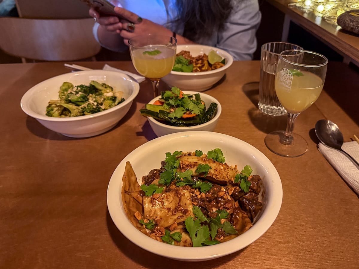 a plate of noodles topped with cilantro and some other small bowls of appetizers behind it
best restaurants in almaty, kazakhstan