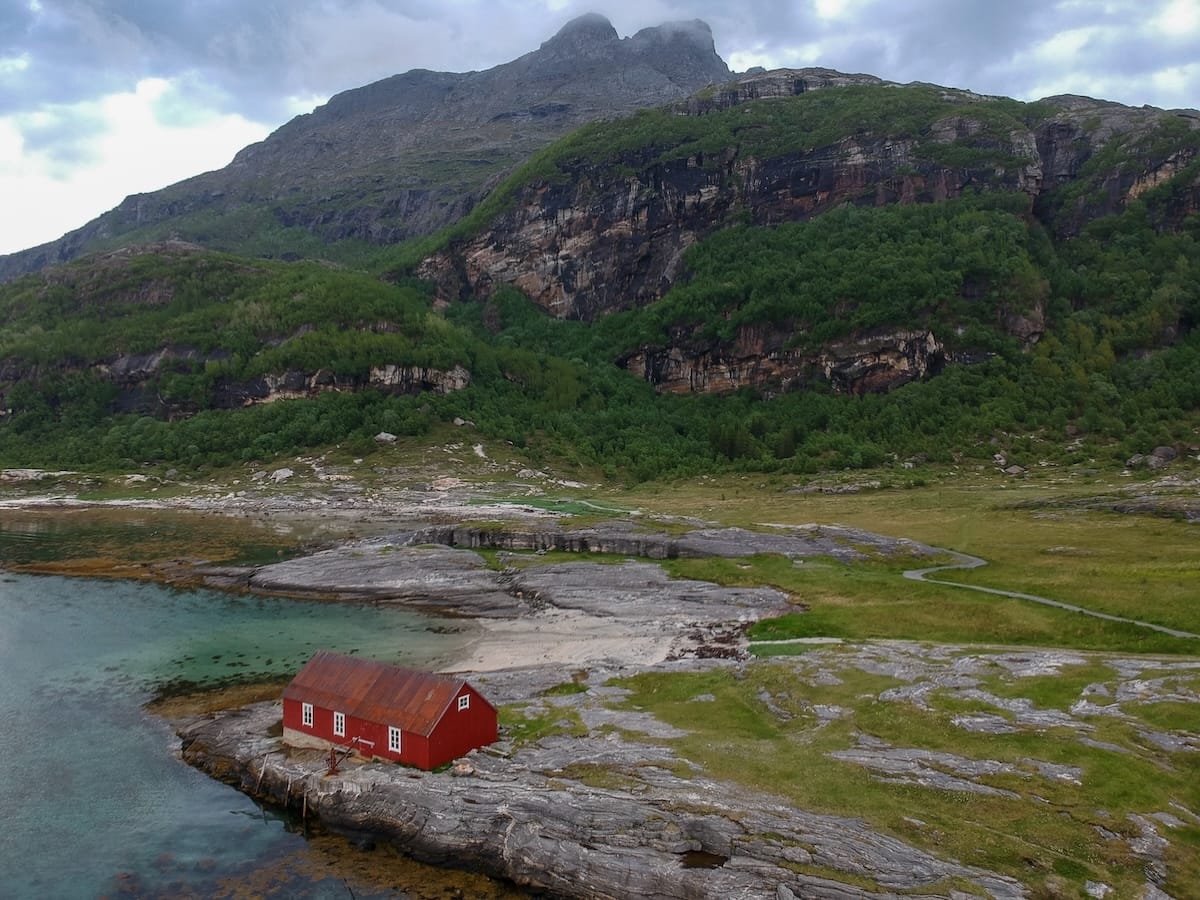 This is a drone photo of a red wooden building by Mjelle Beach in Norway
