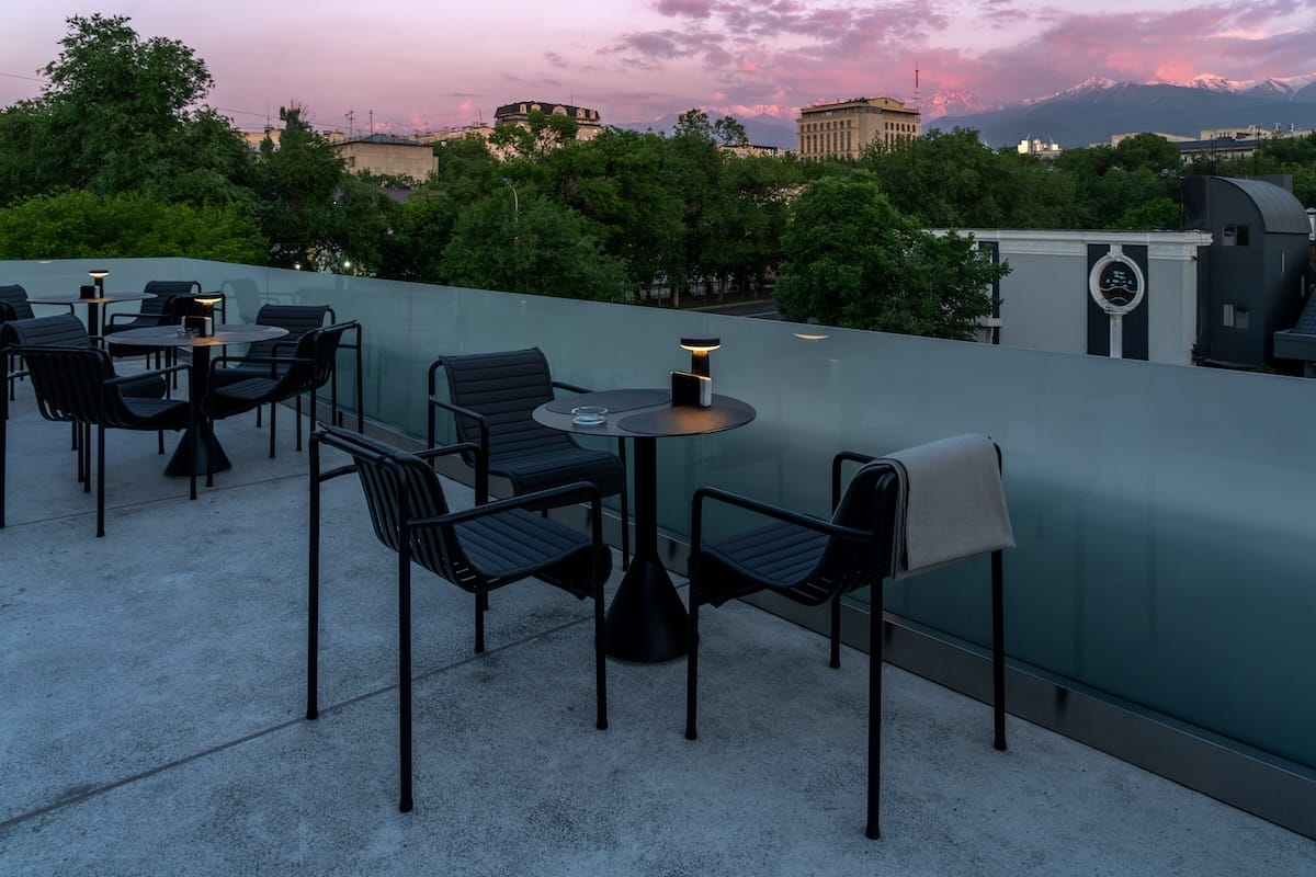 a terrace at a restaurant with pink skies under mountains