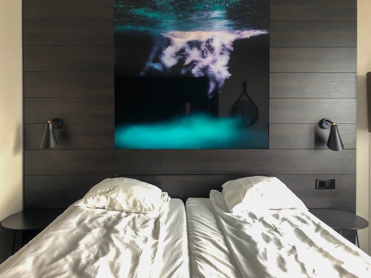 This is a photo of a hotel room with two beds and a northern lights photo in the backdrop