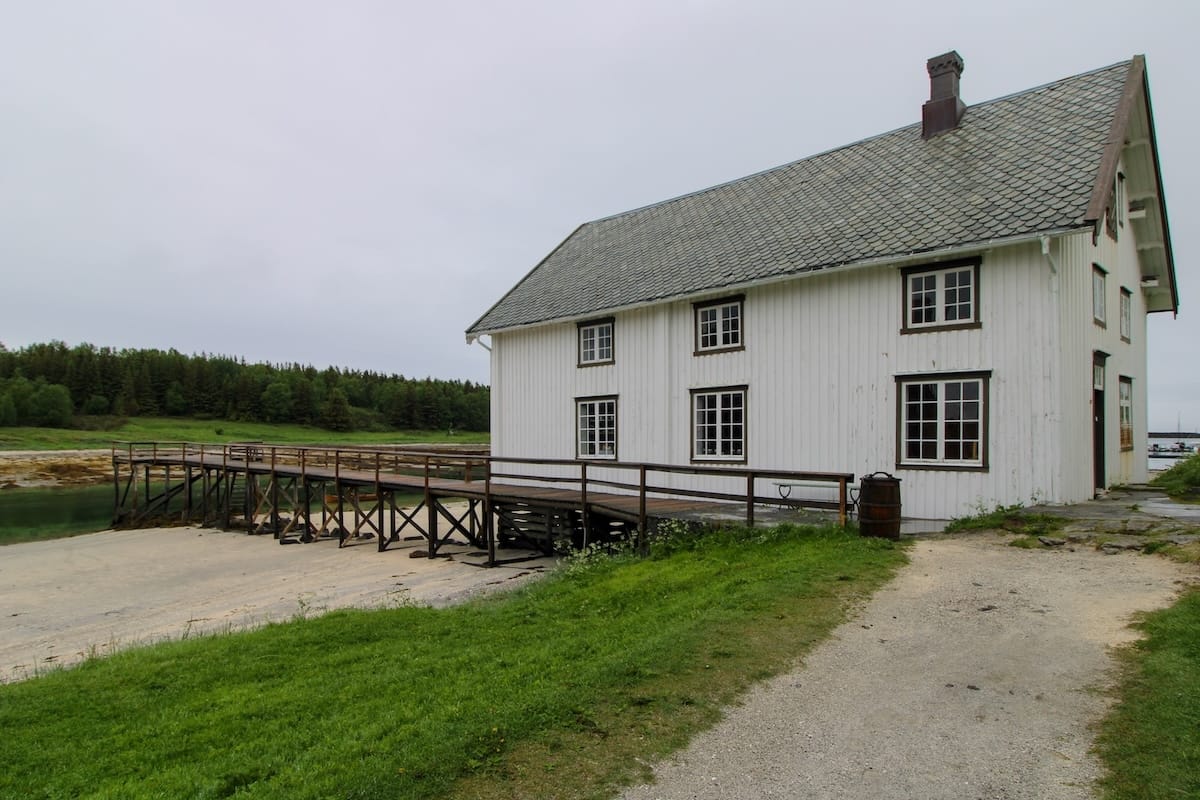 This is a picture of a white wooden historic building with a brown wood deck going to it
