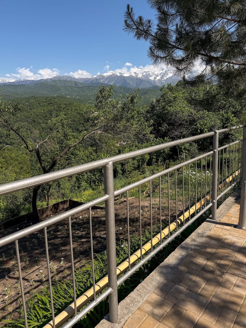 a railing with views of tall mountains in the background