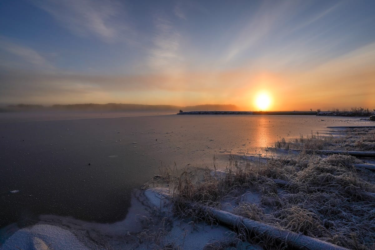 a photo of a lake that is foggy with a low horizon sun