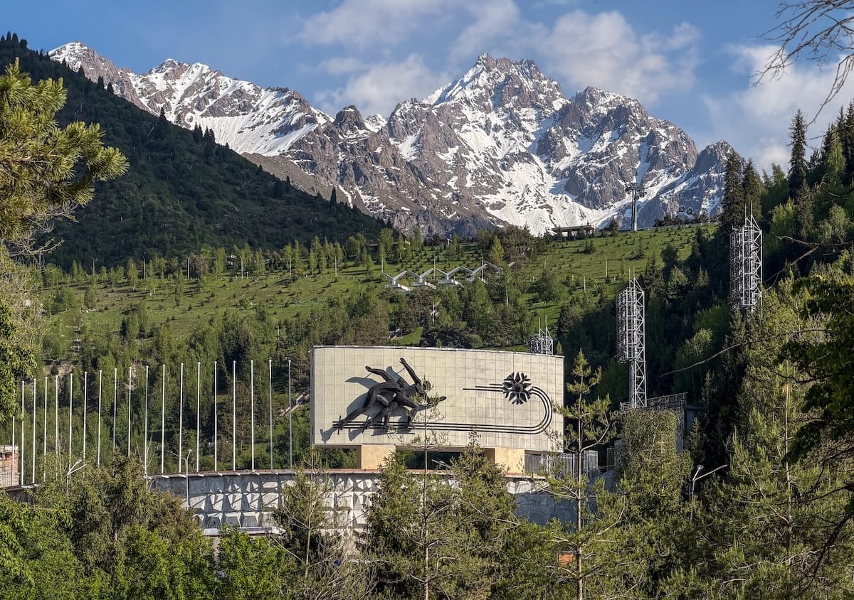 tall mountains with a soviet-era sign in front of it at an ice skating rink