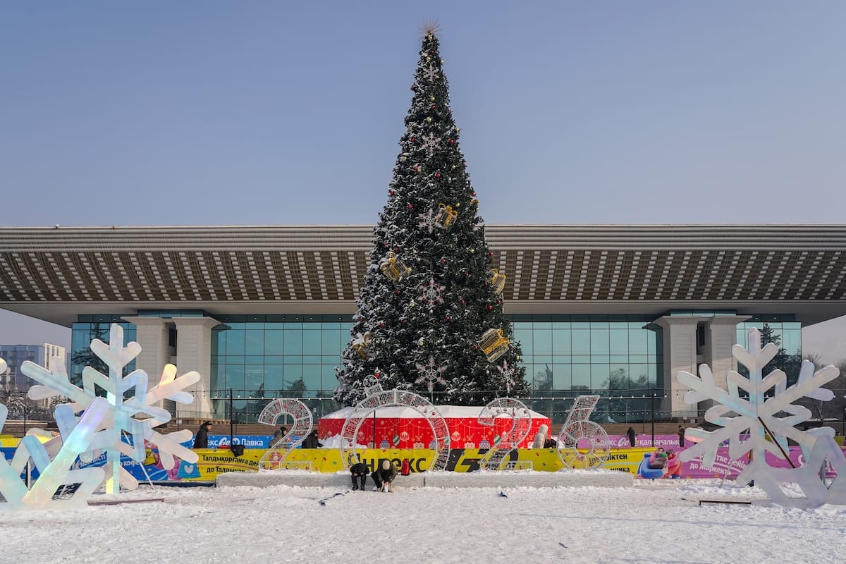 a large christmas tree in front of a spacious building in kazakhstan