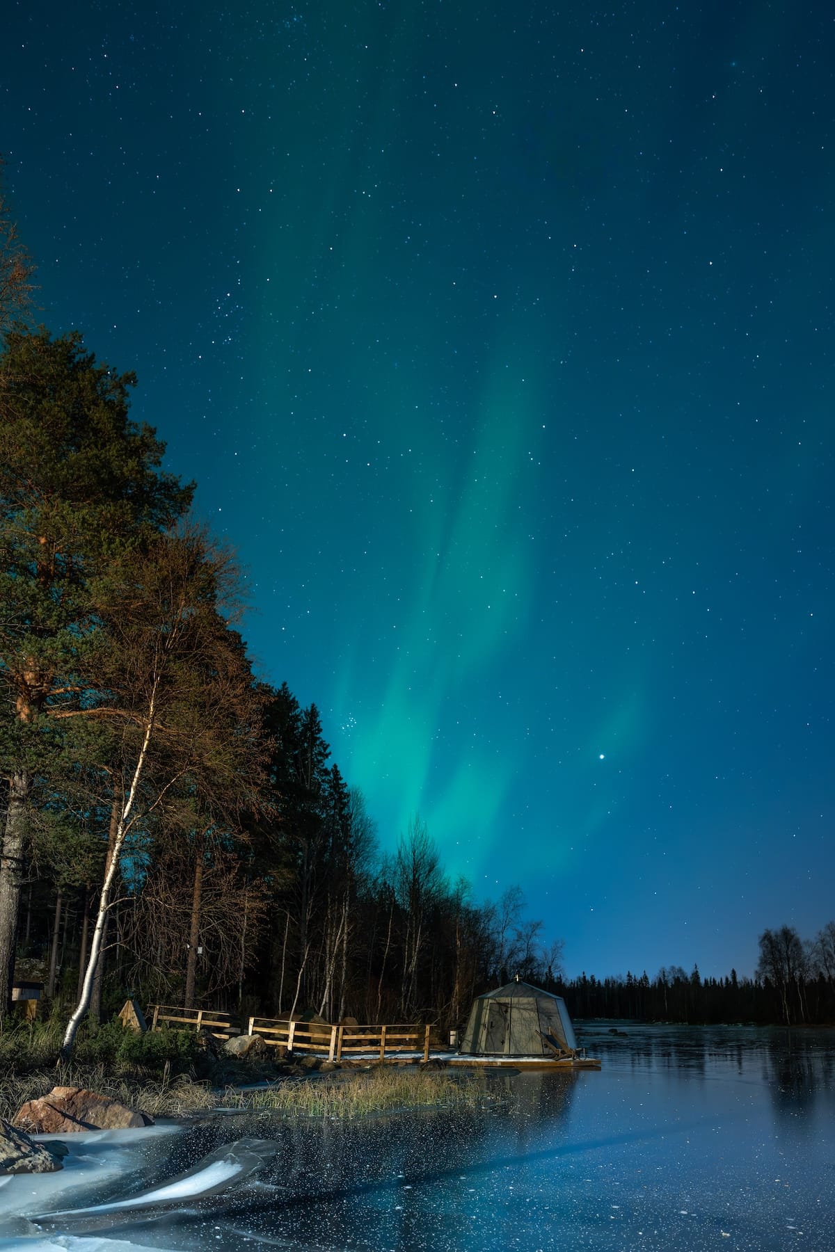 faint northern lights over an igloo in lapland along a river