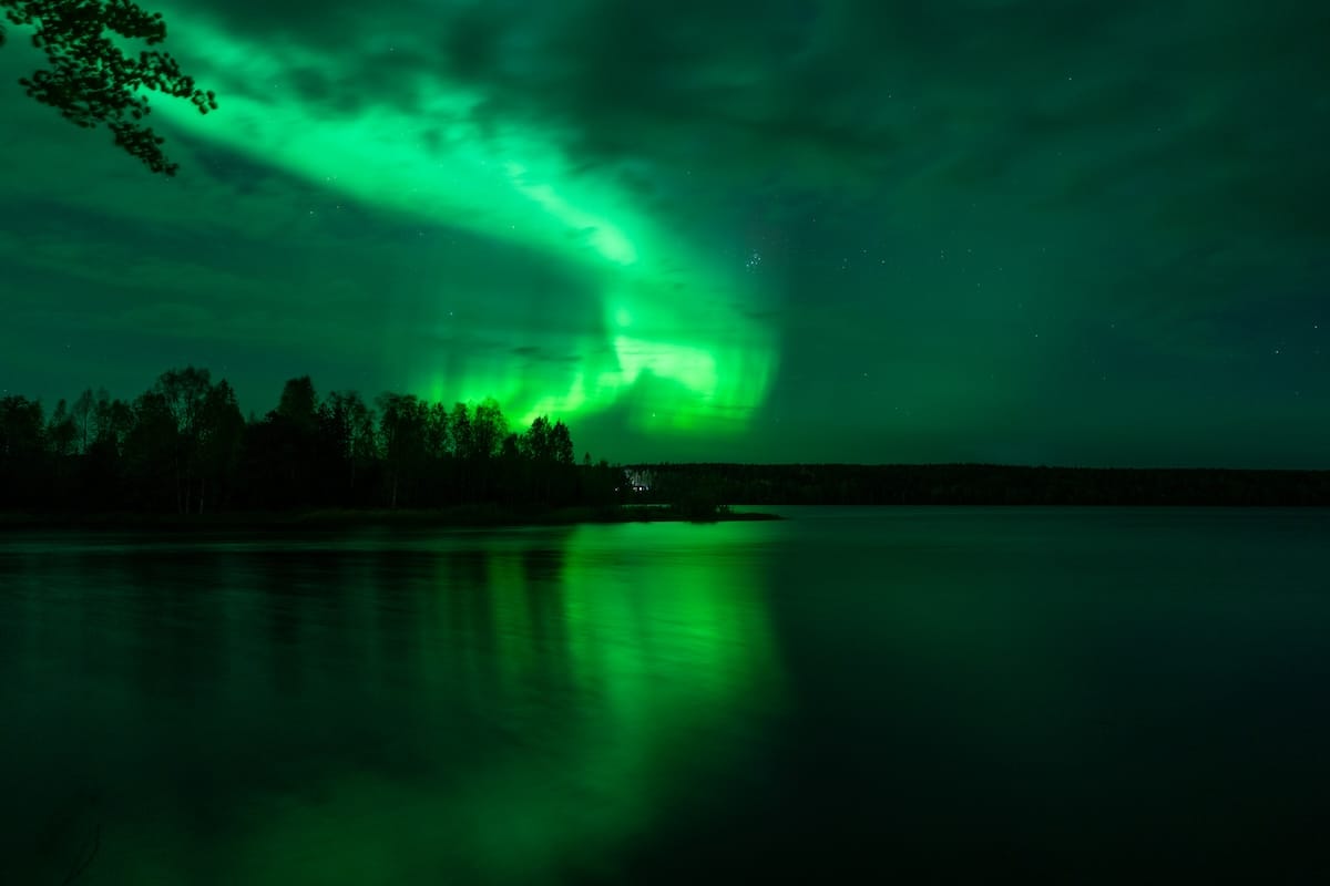 a picture of a green aurora over a lake in lapland