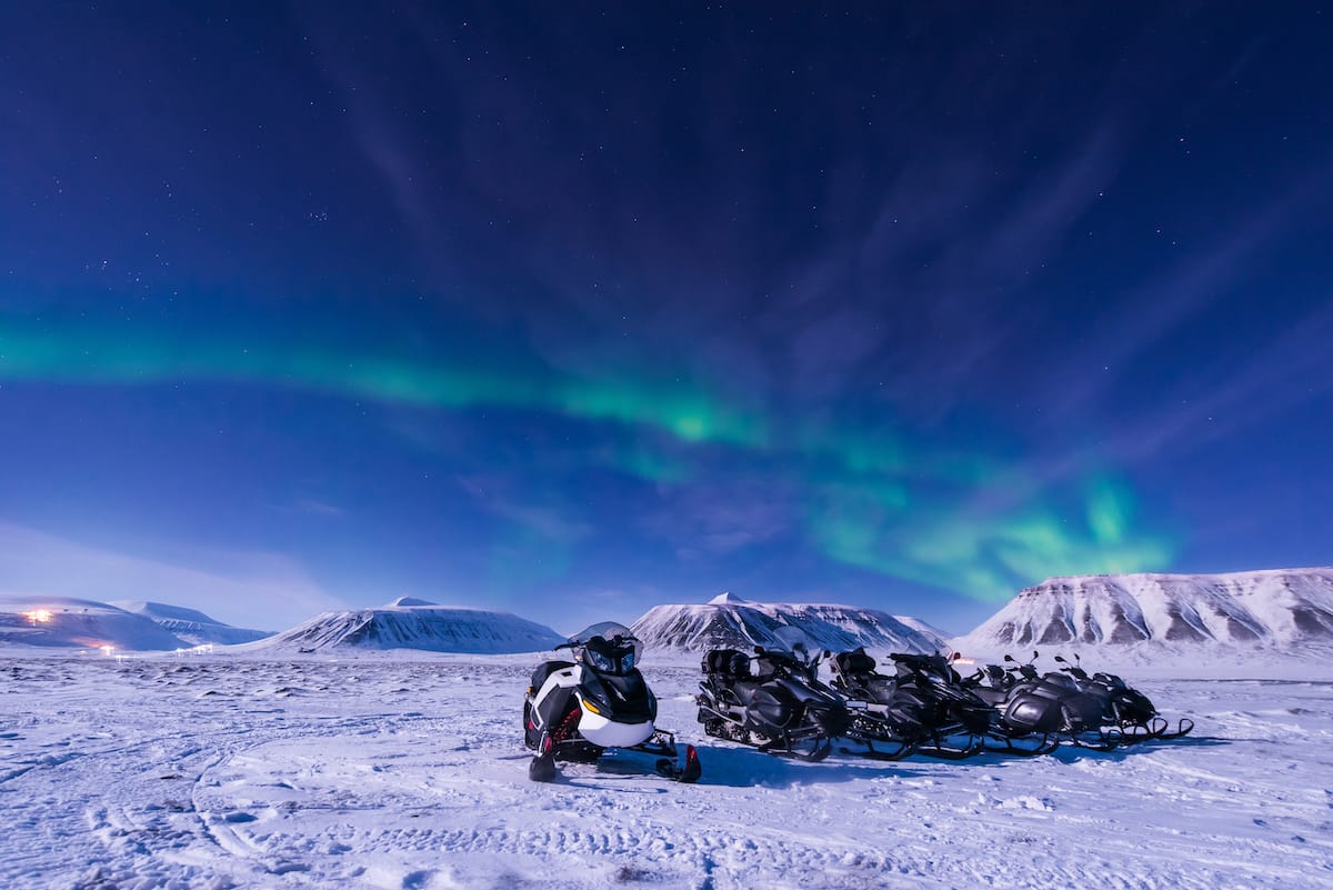 Snowmobiling in Svalbard under the aurora