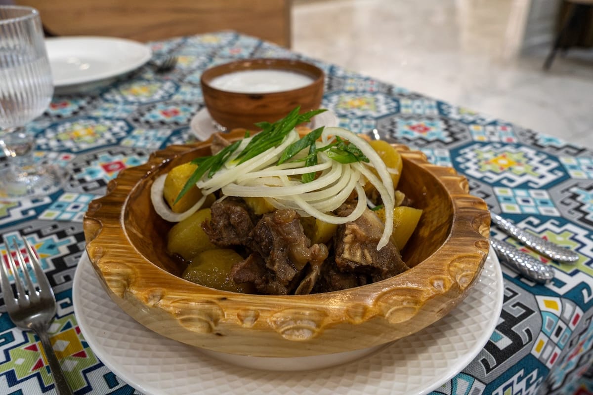 a cup of shubat (in back) with camel and potatoes and onions in a bowl in front
best restaurants in almaty, kazakhstan