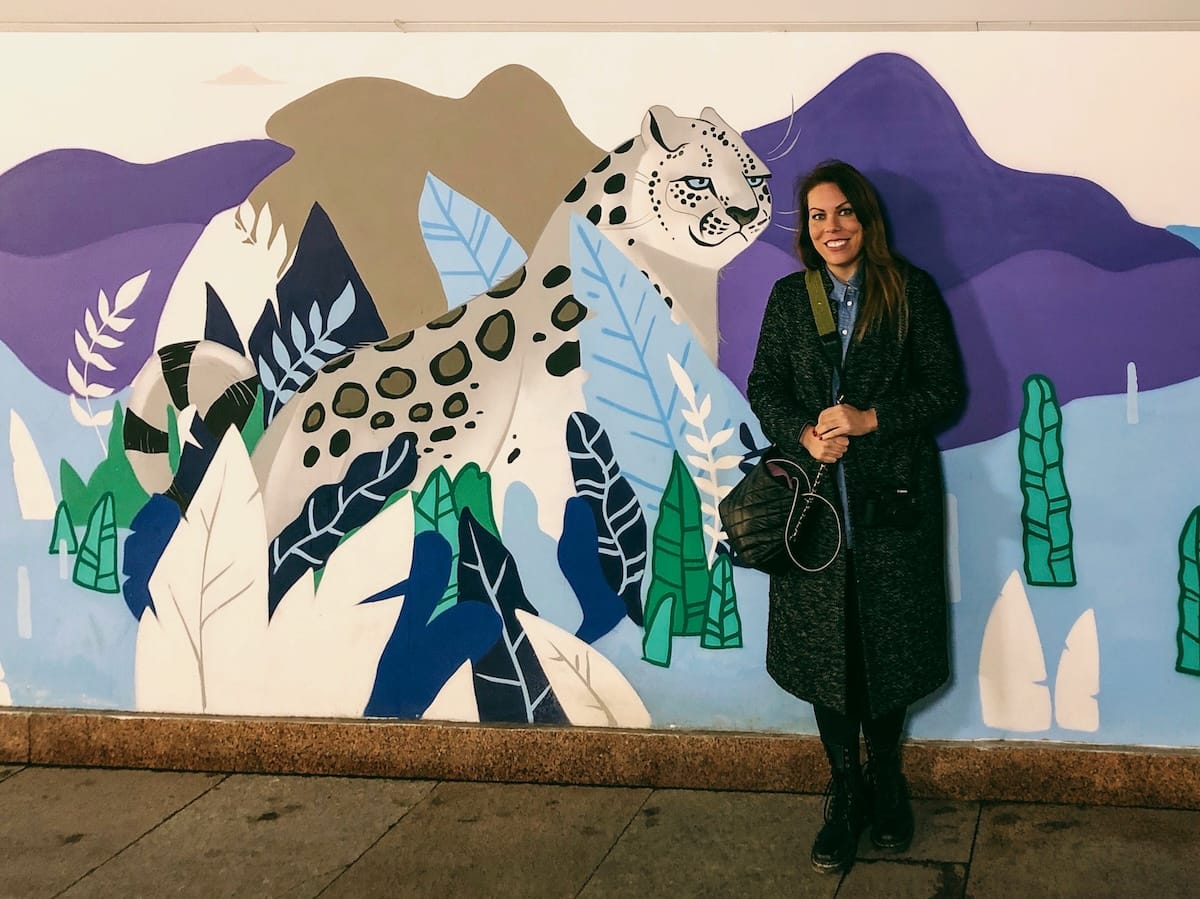 a woman standing in front of a mural of a snow leopard