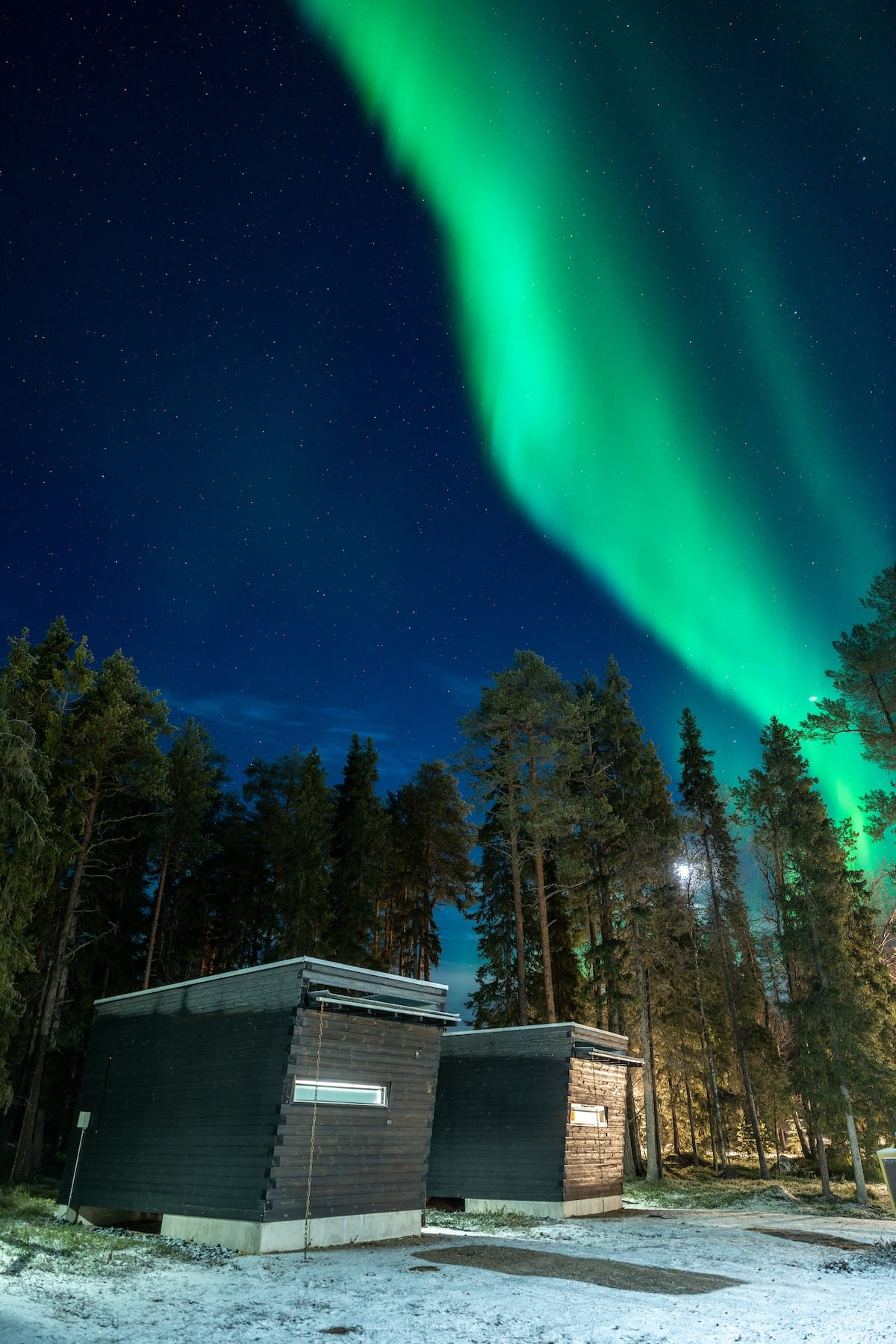 the northern lights over lapland at a resort with small black cabins