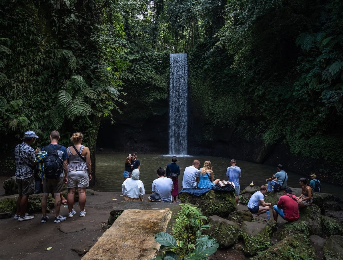 A crowd in front of Tibumana Waterfall in Bali - no one is swimming in the pool and everyone is standing around on the concrete