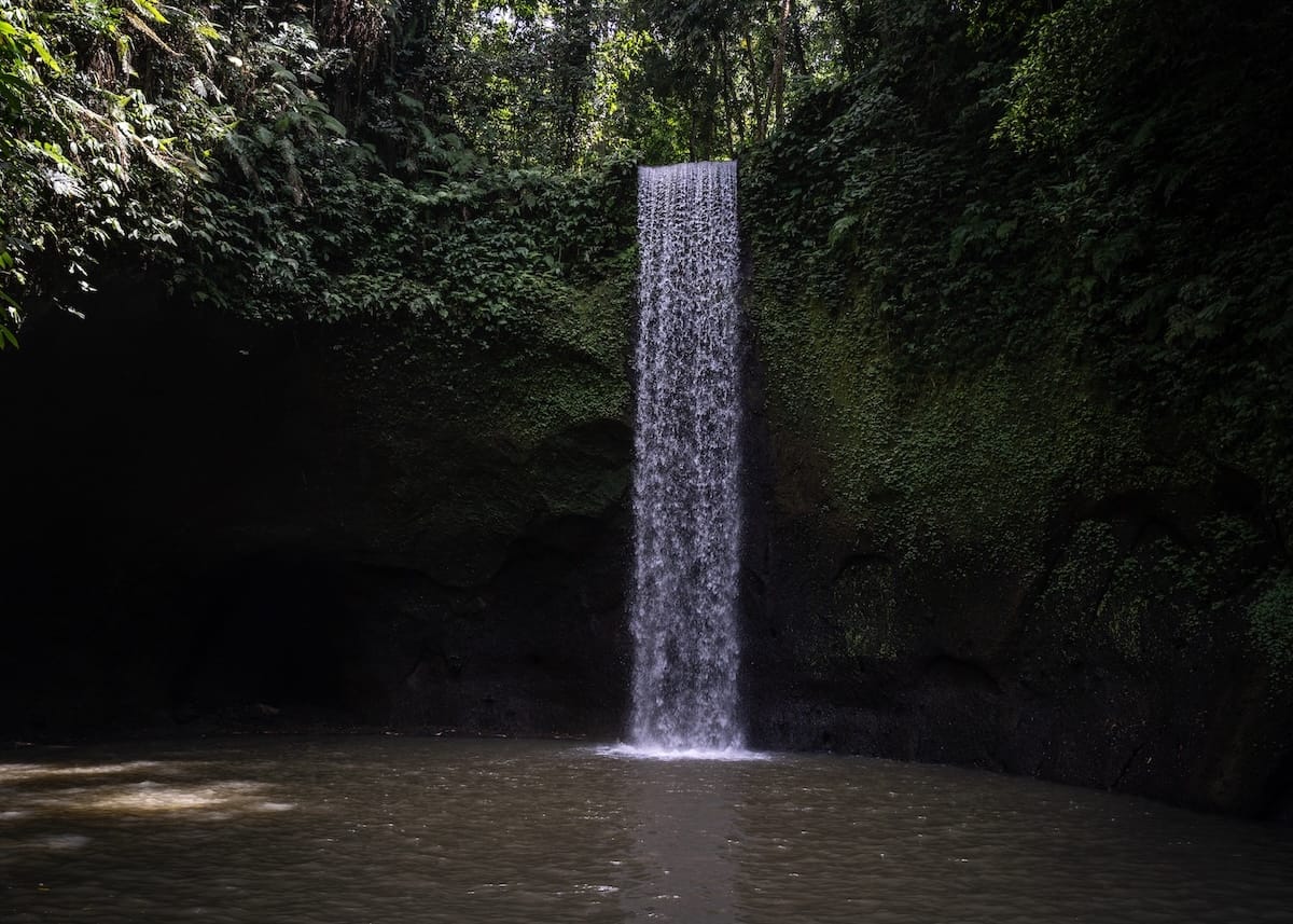 How to Visit Tibumana Waterfall in Bali
This is a photo of the waterfall streaming down into a brown pool of water.