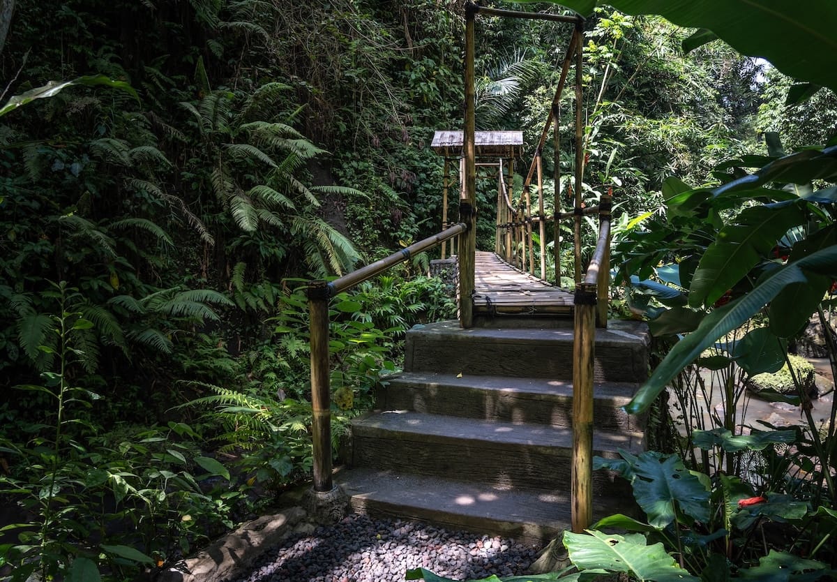 This is the entrance to a bamboo bridge leading to Tibumana Waterfall. There is jungle surrounding it.