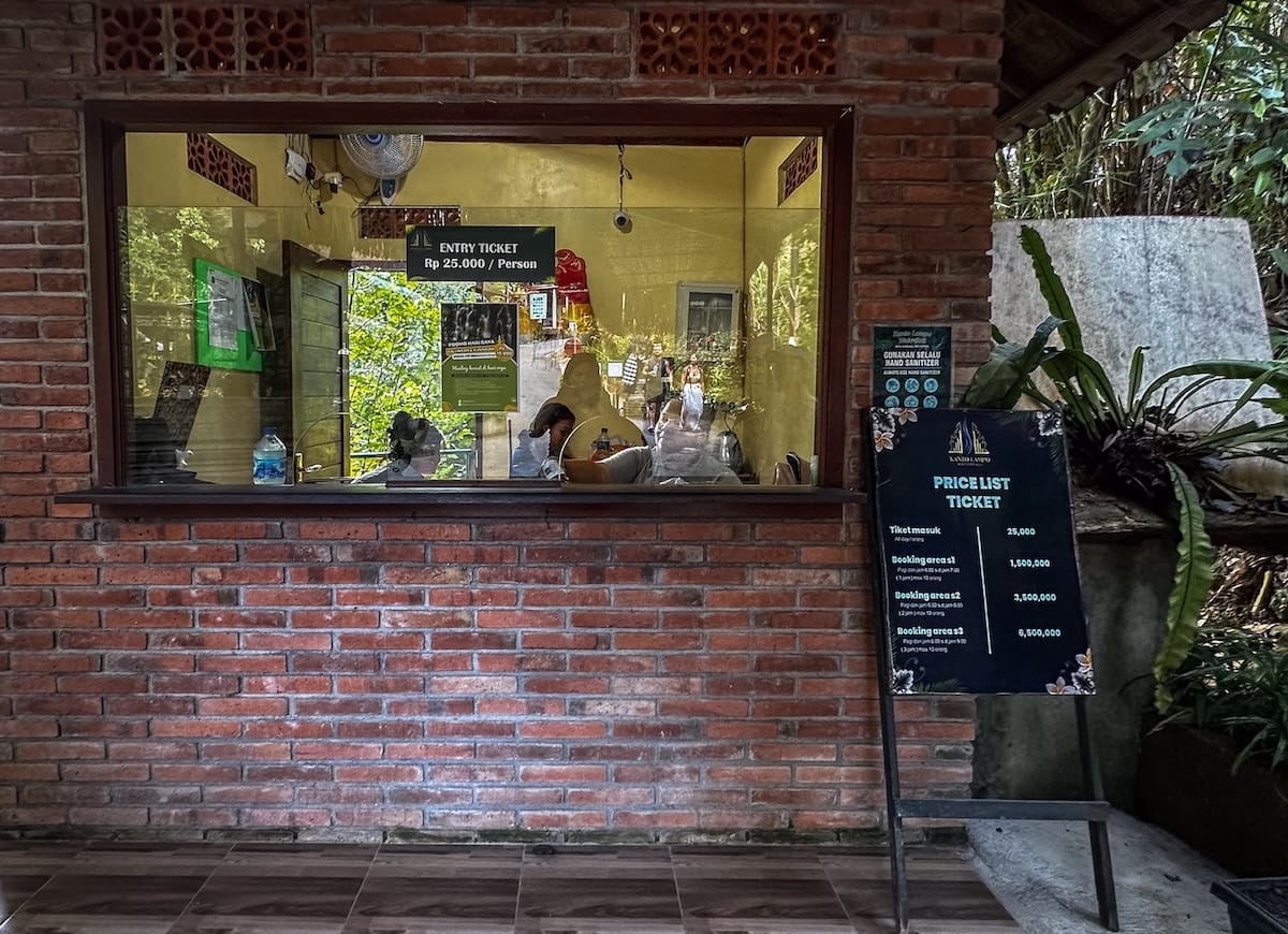 This is a ticket counter behind a brick wall and glass at Kanto Lampo Waterfall