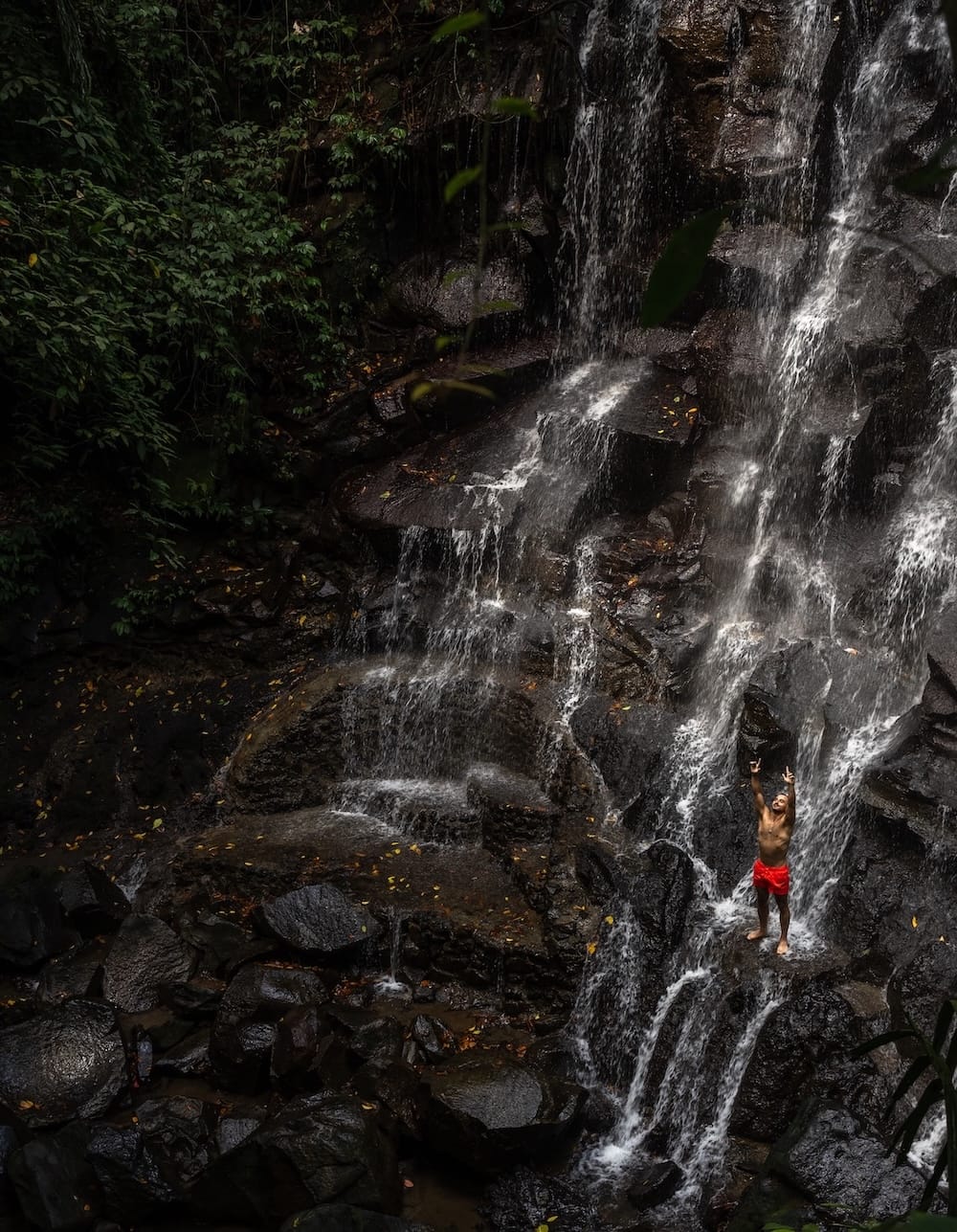 A person standing in front of Kanto Lampo Waterfall in Bali