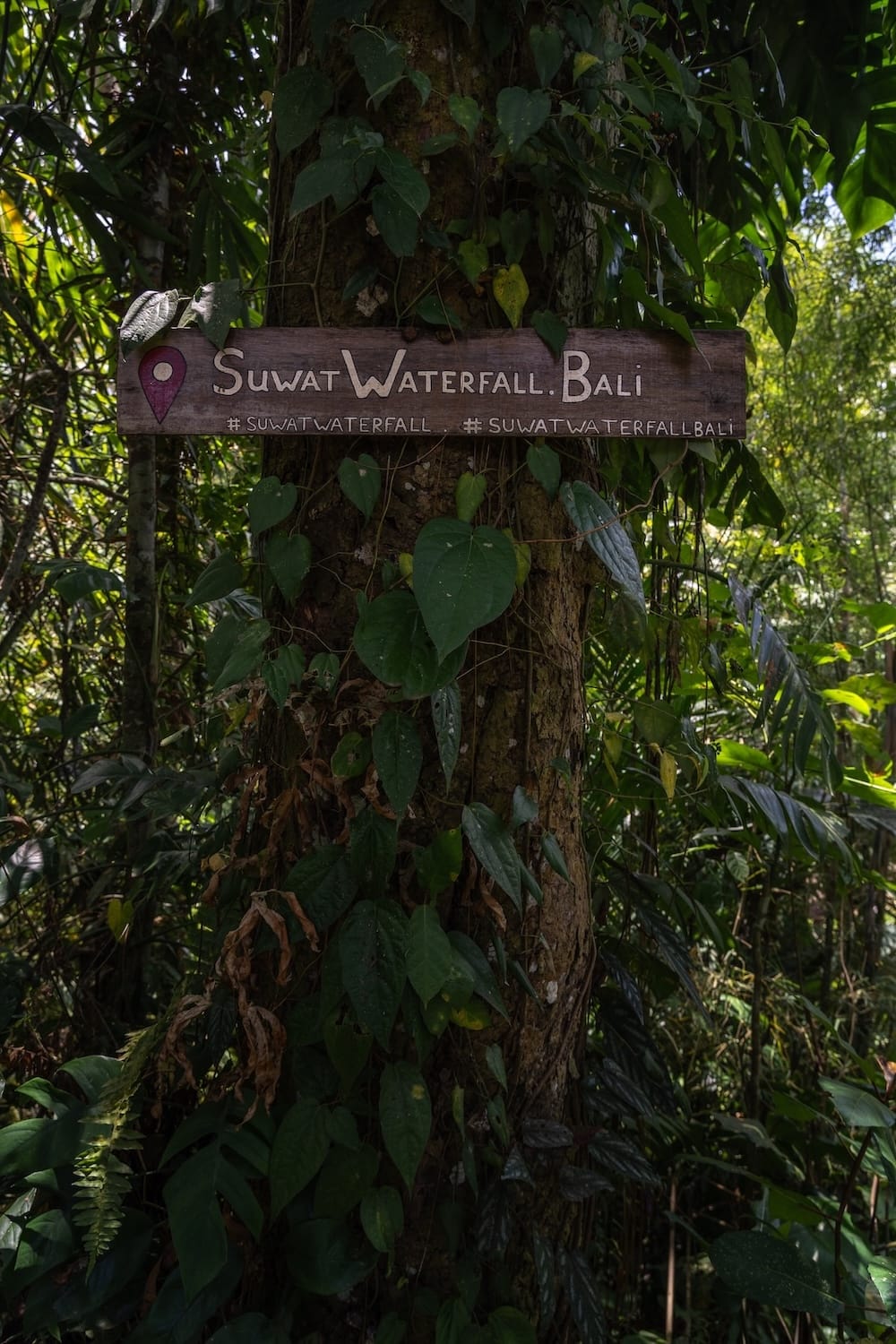 A sign indicating that you are going to Suwat Waterfall in Bali. Surrounded by greenery