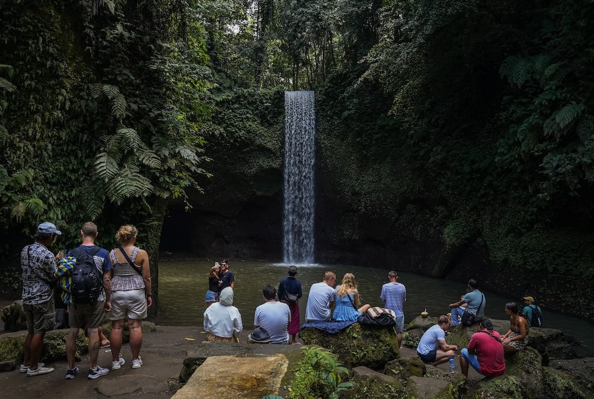 This is a waterfall in Bali called Tibumana and there are a lot of people standing in front of it