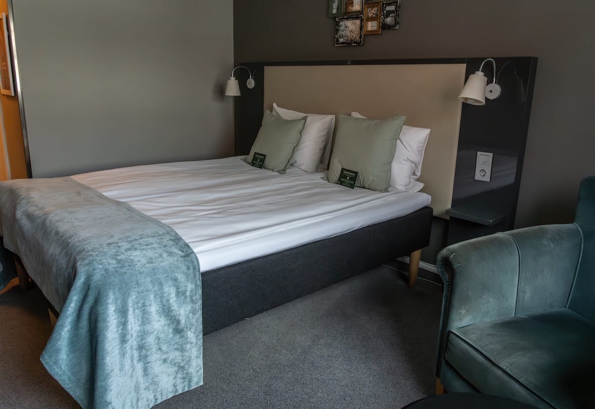 Bed in a room at Scandic Bryggen in Honningsvåg.
This is a photo of a bed with a light green/blue decoration, white sheets, and pillows.