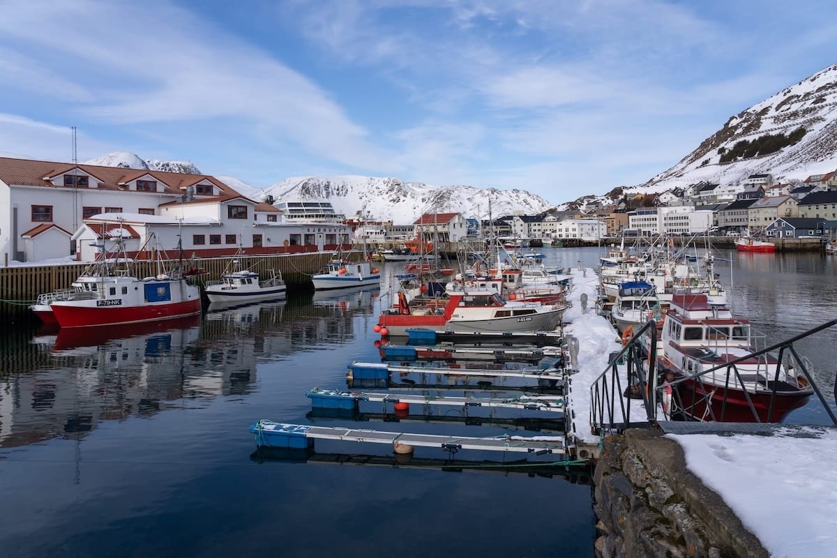 The harbor in Honningsvåg, Norway. There are boats, snowy mountains, and slips for the boats in this photo.
Scandic Bryggen Review