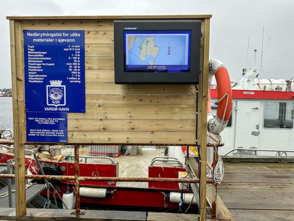 An area in Vardø by the harbor - there is a sign and a TV screen.