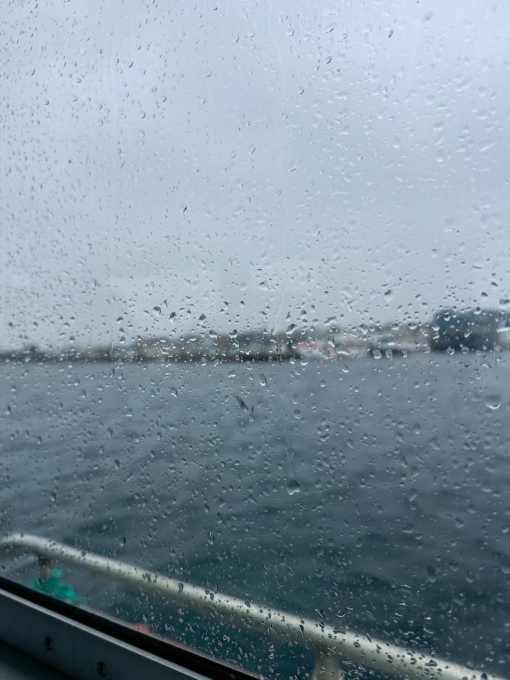 A photo of rain out of a window in a harbor in Vardø, Norway