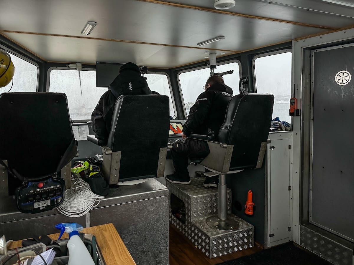 Inside a small boat with two male crew members