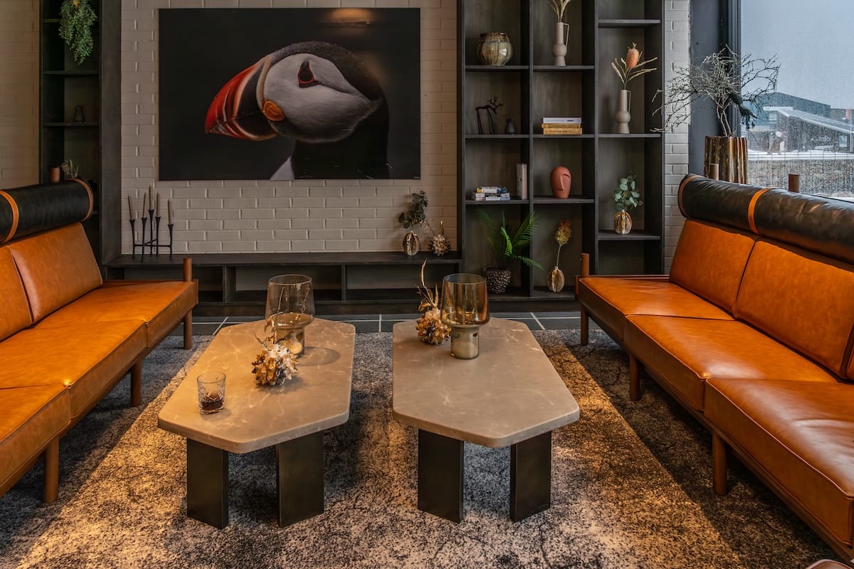 This is a photo of a hotel lobby with orange leather couches and a picture of a puffin on the wall
