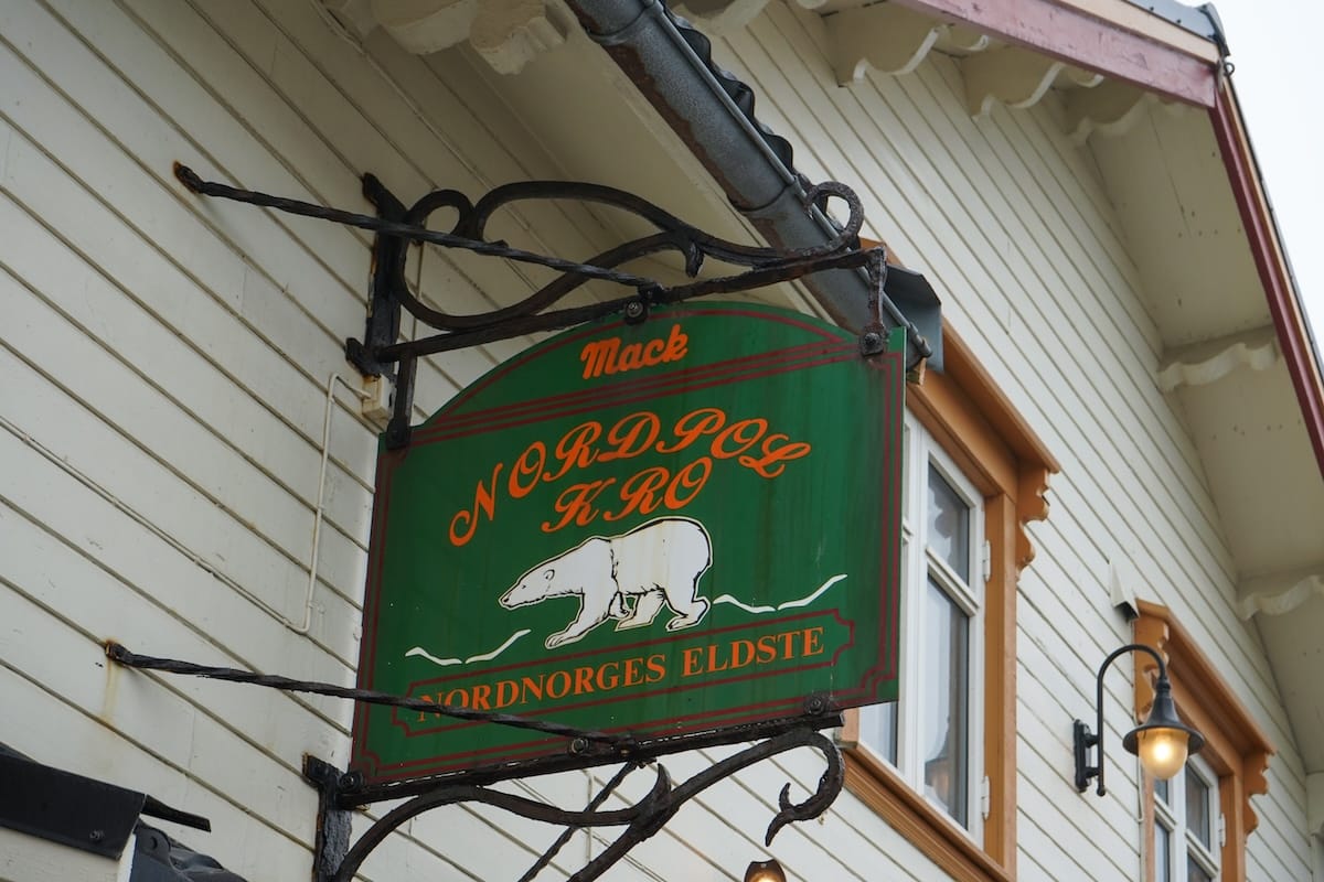 A green sign with red writing and a polar bear indicated that this is 'Nordpol Kro', Northern Norway's oldest pub (written in Norwegian)