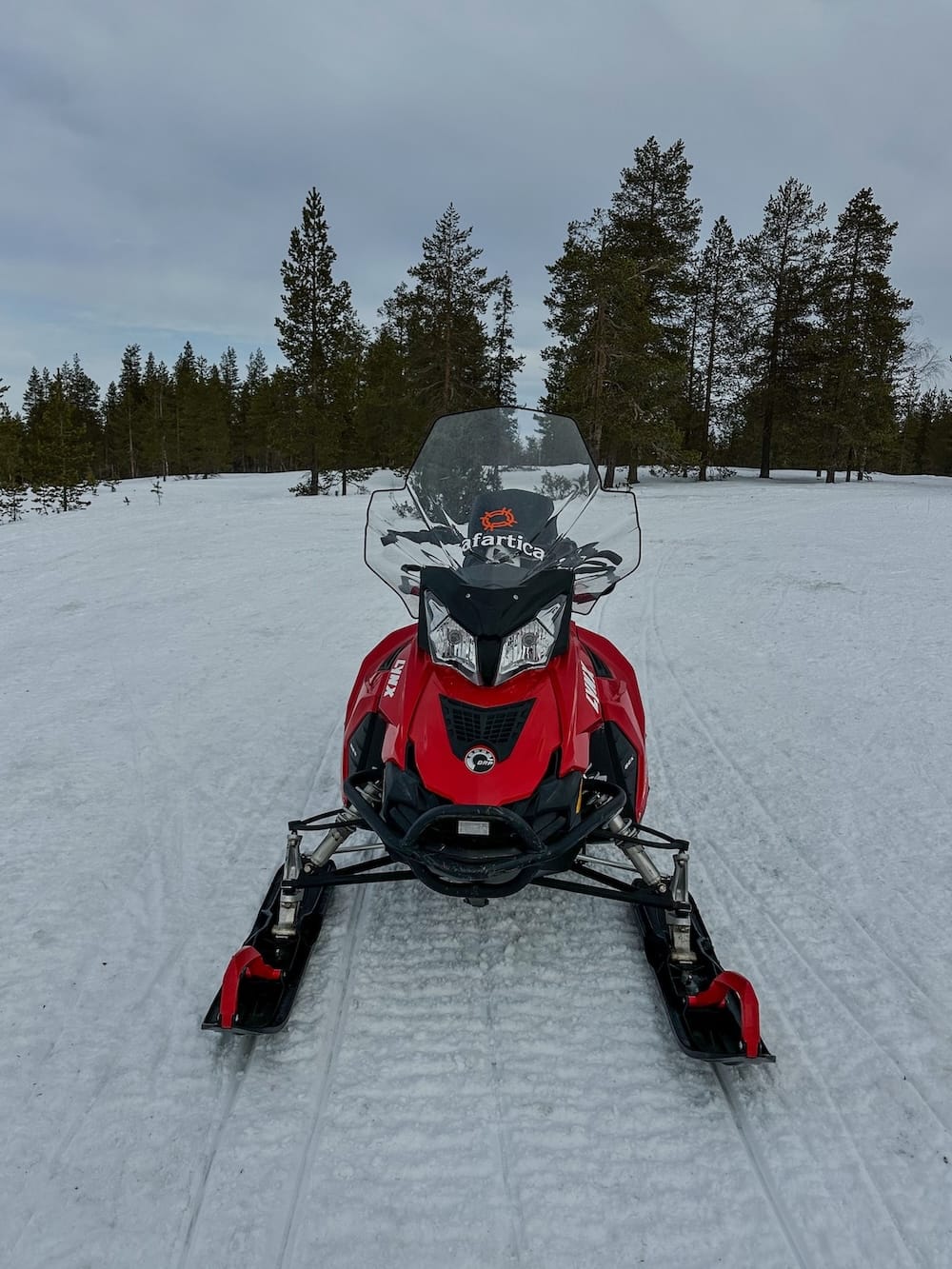 Snowmobiling in Rovaniemi, Finland: Best tours, tips, and what to expect.
Photo: this is a red Lynx snowmobile without anyone on it in a snowy forest in Rovaniemi, Finland