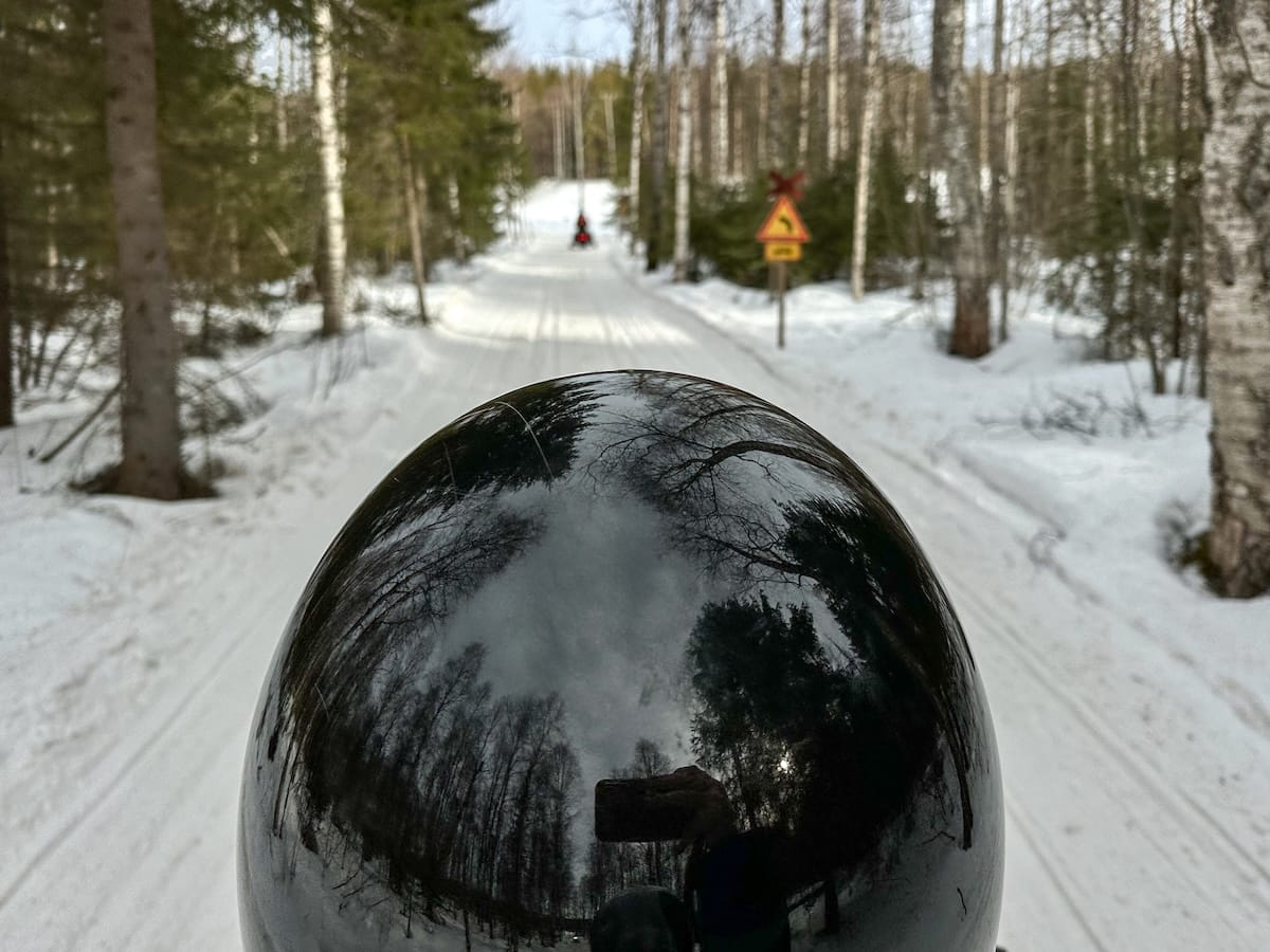 Snowmobiling in Rovaniemi, Finland: Best tours, tips, and what to expect.
Photo: a man snowmobiling through the finnish forest - this is the back of his helmet.