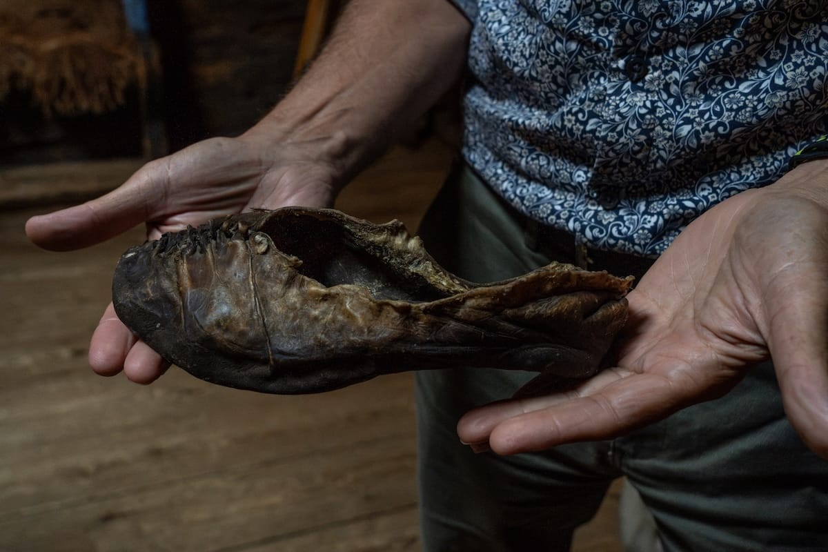 an old leather shoes in the hands of a man in an old building.