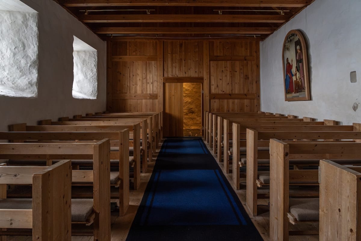 inside a minimalistic church in the faroe islands with blue carpet and wooden benches