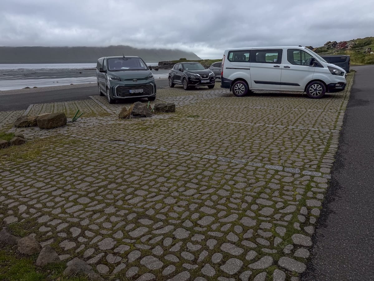 a parking lot along a seafront with a few cars and vans