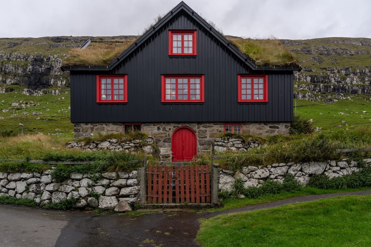 What to know before you visit Kirkjubøur in the Faroe Islands a black house with red door and shutters in the faroe islands