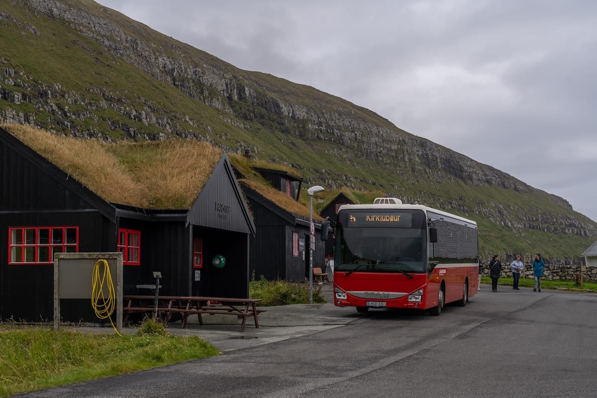 a red bus sitting outside a visitor center in Kirkjubøur, Faroe Islands