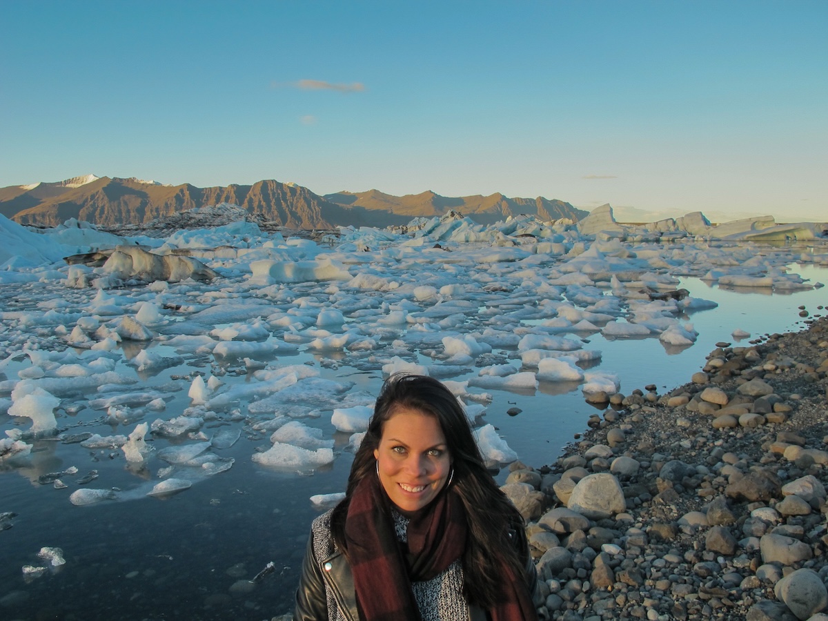 A young woman standing in front of Jökulsárlón glacier lagoon in Iceland in a scarf with a jacket