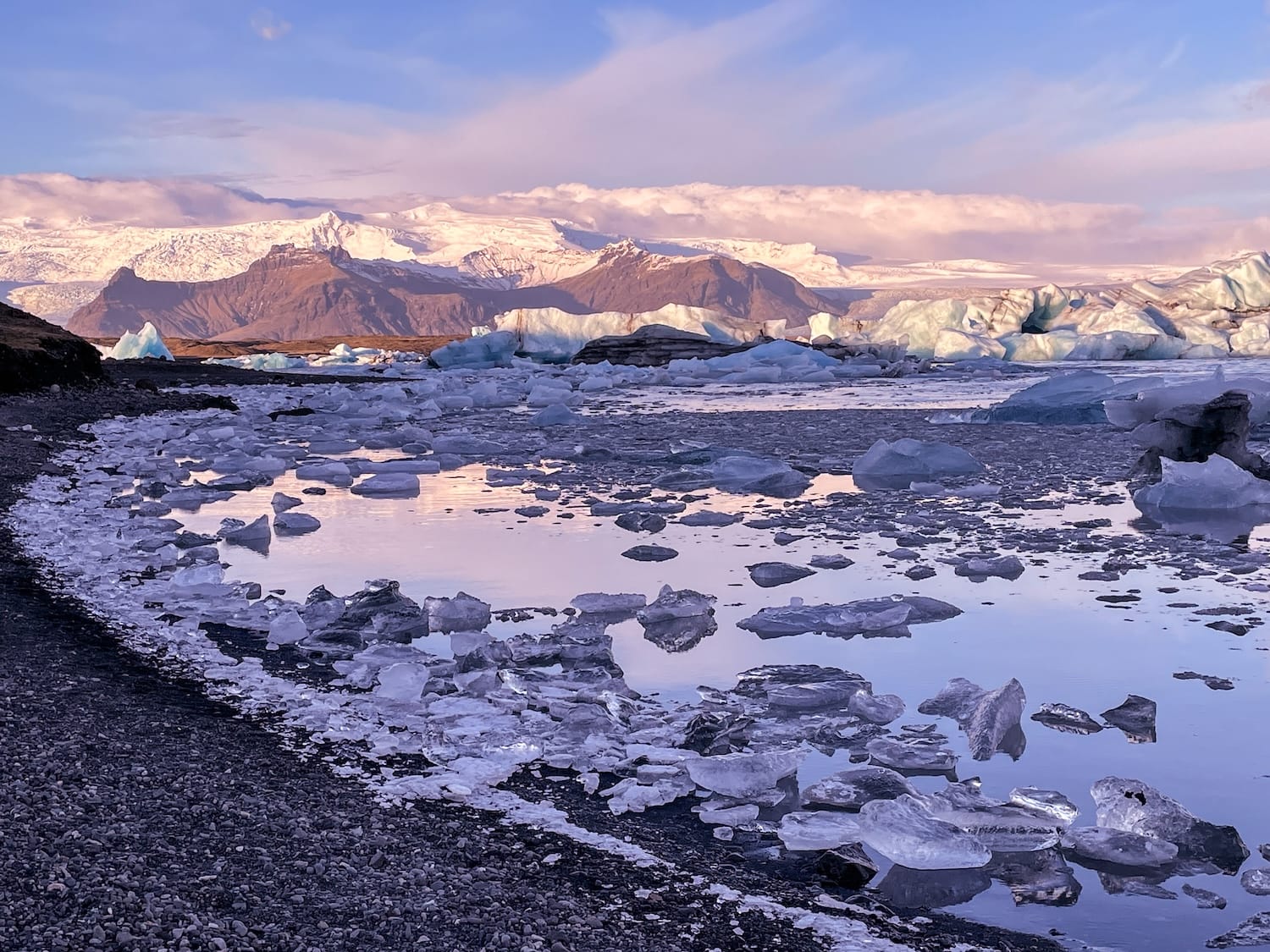 How to Visit Jökulsárlón Glacier Lagoon in Iceland
This is a photo of a blue/purple sky in front of the glacier lagoon in iceland. Lots of icebergs scattered in the water