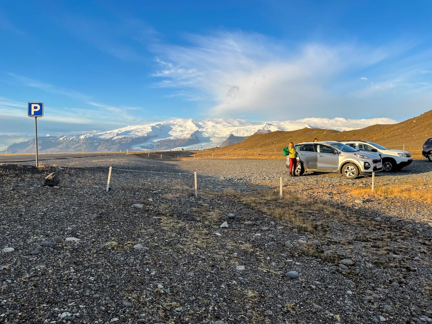 This is a blue sky with a parking lot and a car parked at Diamond Beach in Iceland