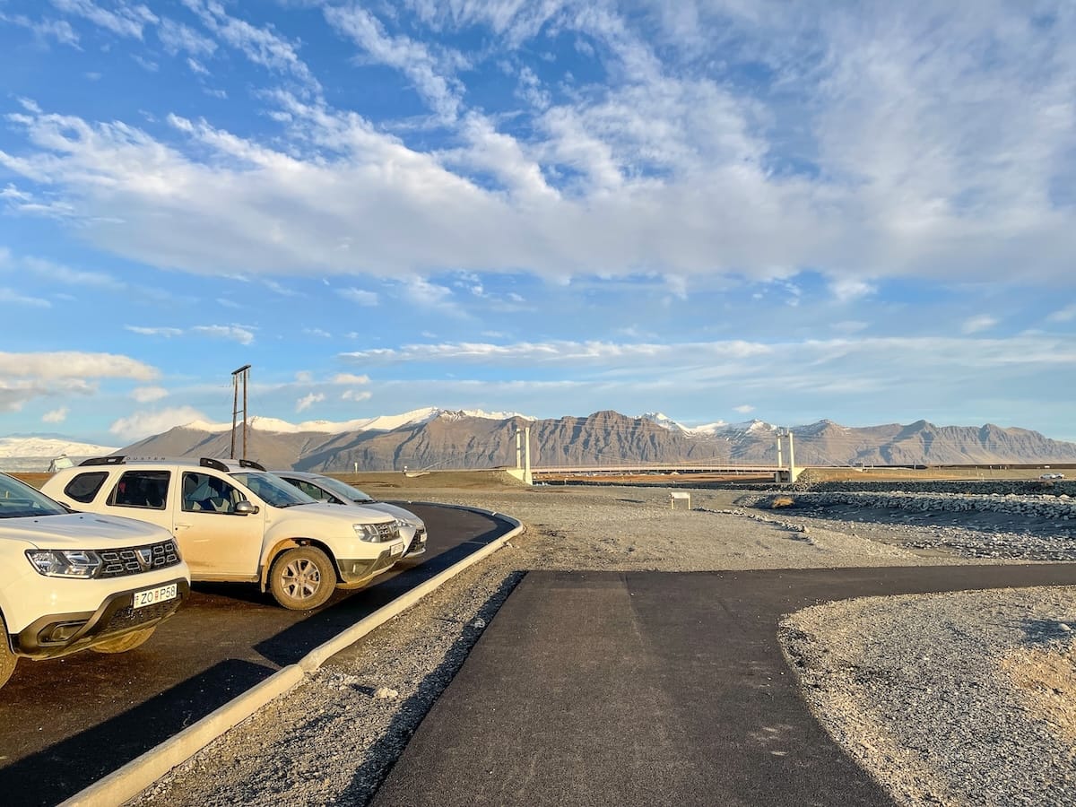 This is a parking lot at Diamond Beach Iceland... blue skies and not much more around except the two cars parked there