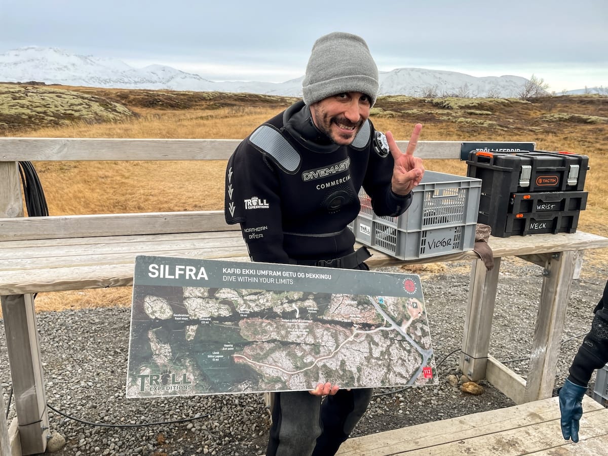 This is a tour guide with a hat on and Troll Expeditions suit showing the Silfra fissure on a map before a tour