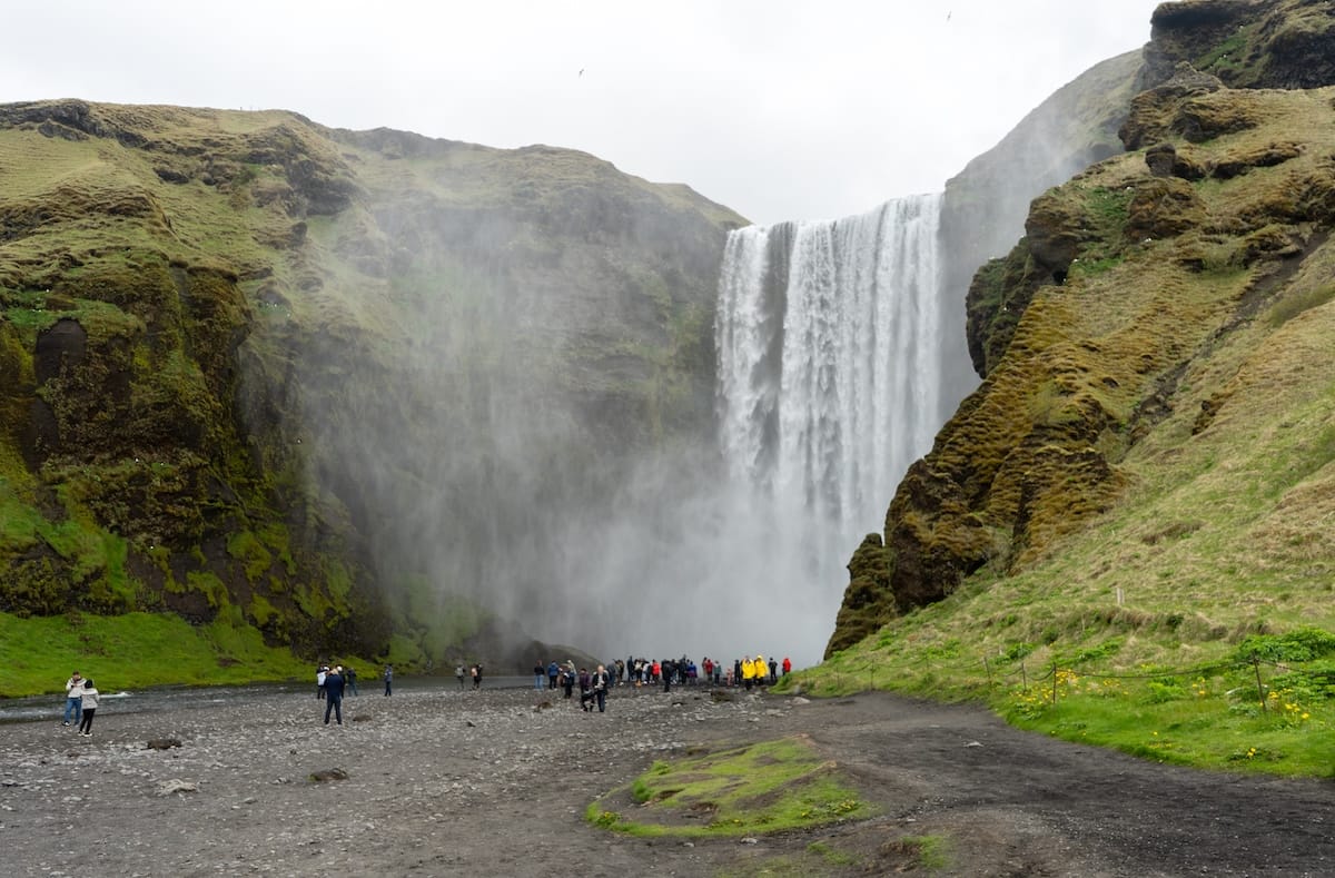 Photo is of Skógafoss waterfall in Iceland - there are many tourists and the waterfall is very powerful since it is spring