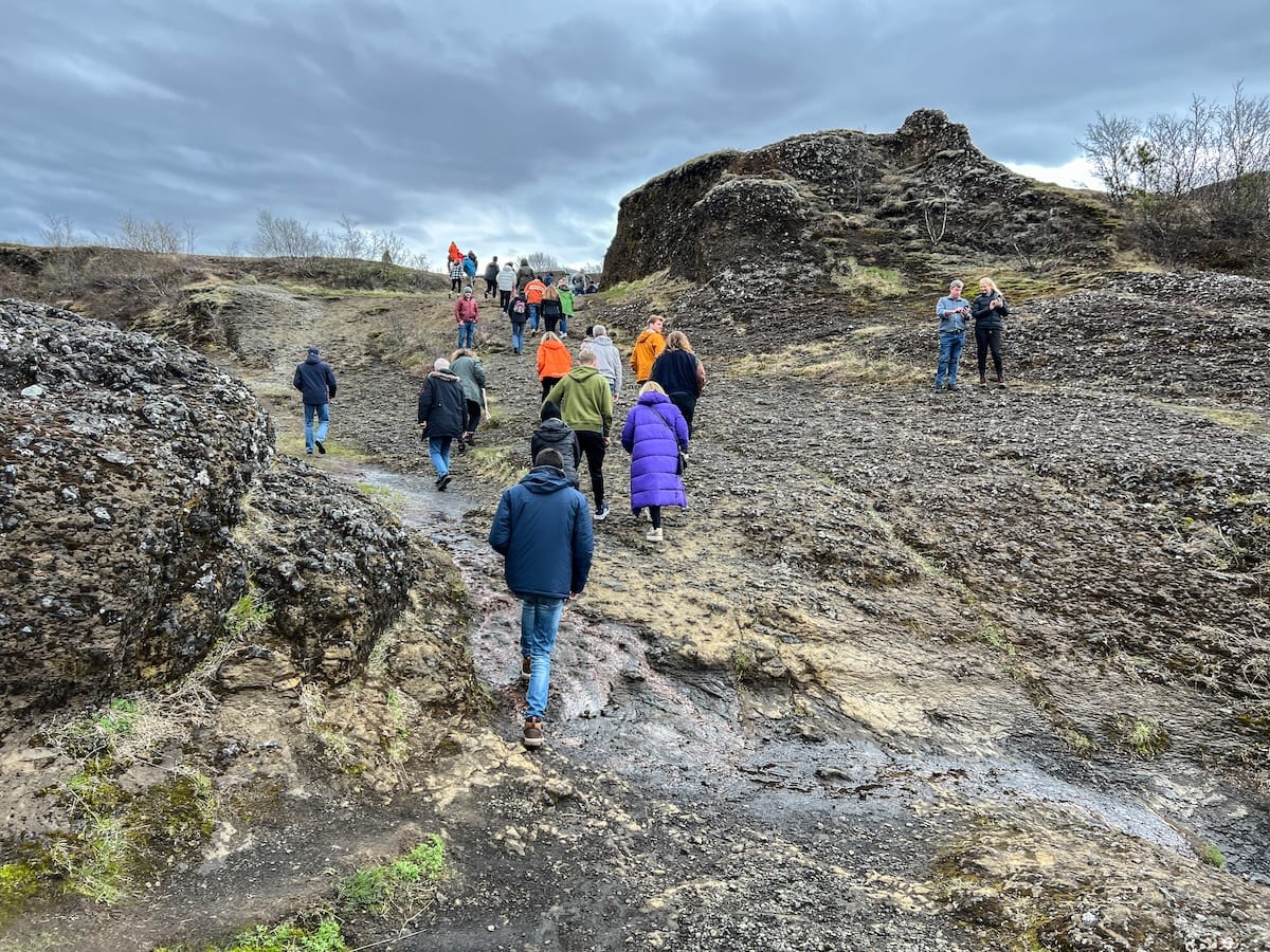Photo is of tourists in a bleak and brown landscape along Iceland's Golden Circle - taken during May