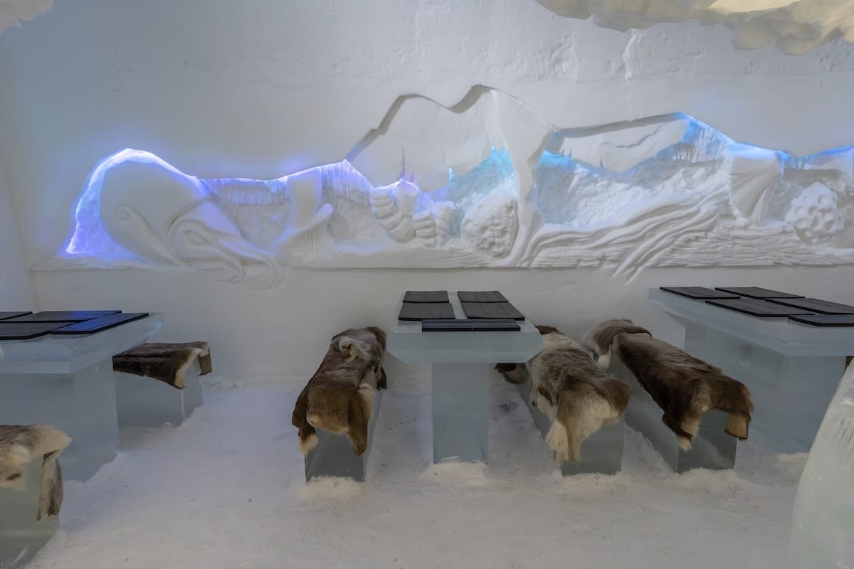 Visiting the Arctic SnowHotel in Rovaniemi
______

inside an ice restaurant with benches with reindeer skins on them